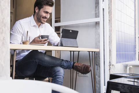 Junger Mann benutzt Tablet in einem Café, lizenzfreies Stockfoto