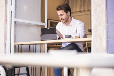 Young man using tablet at a cafe - UUF20359