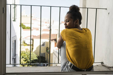 Young woman sitting on a balcony - UUF20360