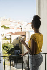 Young woman with coffee cup on a balcony - UUF20363