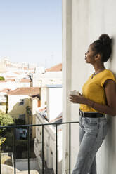 Young woman with coffee cup on a balcony - UUF20364