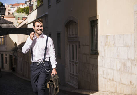 Smiling young man with earbuds in the old town, Lisbon, Portugal stock photo