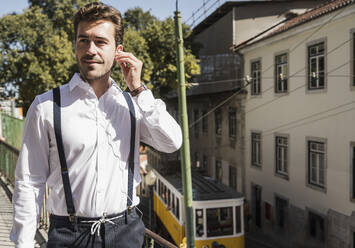 Young man with earbuds in the city, Lisbon, Portugal - UUF20372
