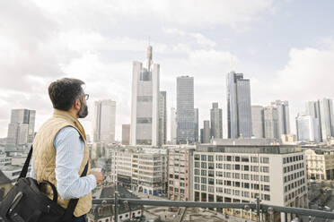 Mann auf Aussichtsterrasse mit Blick auf Wolkenkratzer, Frankfurt, Deutschland - AHSF02467