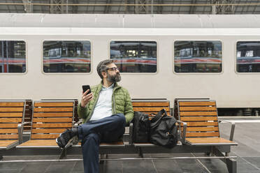 Mann sitzt auf einer Bank am Bahnhof - AHSF02473