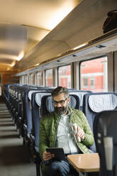 Man sitting in train using tablet - AHSF02481