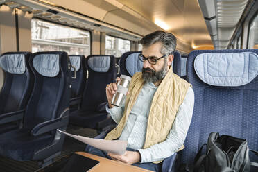 Man sitting in train reading documents - AHSF02489