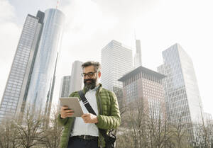 Mann mit Tablet vor Wolkenkratzern, Frankfurt, Deutschland - AHSF02501