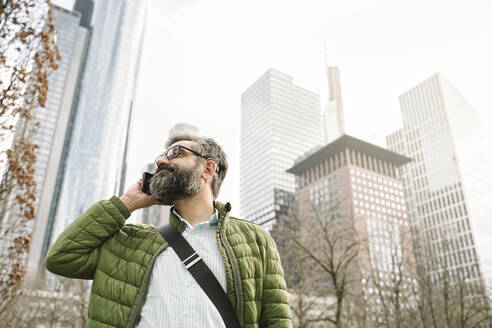 Mann am Telefon vor Wolkenkratzern, Frankfurt, Deutschland - AHSF02502