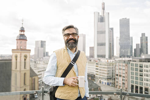 Portrait of smiling man on observation terrace in front of skycrapers, Frankfurt, Germany - AHSF02507