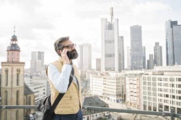Mann am Telefon vor Wolkenkratzern, Frankfurt, Deutschland - AHSF02508