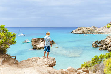 Mann steht auf einer Klippe und schaut aufs Meer, Ibiza, Spanien - KIJF02998
