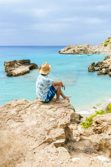 Mann sitzt auf einer Klippe und schaut aufs Meer, Ibiza, Spanien - KIJF02999