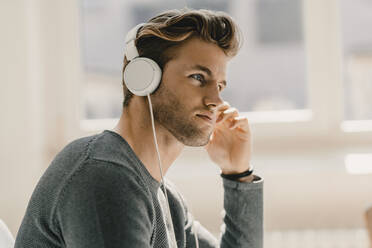 Junger Mann im Büro mit Kopfhörern - KNSF08061