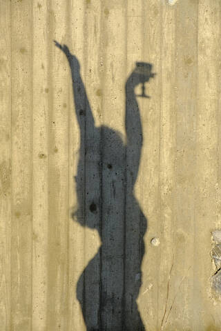 Schatten eines tanzenden Teenagers mit einem Glas Wein, lizenzfreies Stockfoto