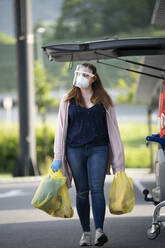 Customer walking with plastic bags at supermarket parking lot - SNF00004