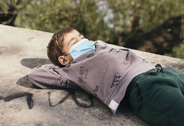 Porträt eines Jungen mit geschlossenen Augen, der sich an einer Wand entspannt - MOMF00865