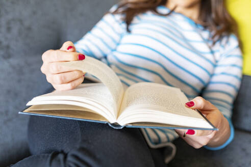 Frau entspannt sich auf dem Sofa und liest ein Buch - WPEF02876