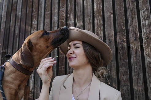 Portrait of woman with hat and her sniffing dog - OGF00382