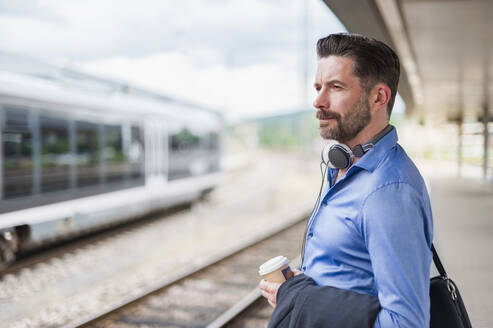 Seitenansicht eines gutaussehenden Geschäftsmannes, der am Bahnhof wartet - DIGF10286