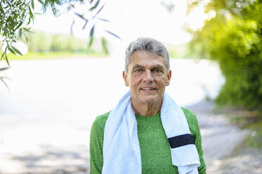 Portrait of confident elderly man standing with towel at park - DIGF10312