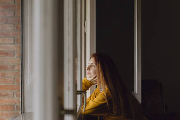 Redheaded woman at open window looking at distance - AFVF06215