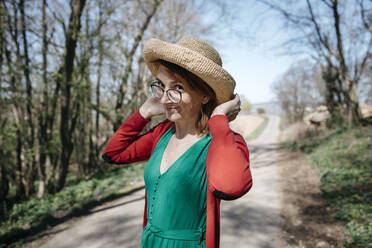 Portrait of smiling mature woman wearing straw hat - KMKF01305