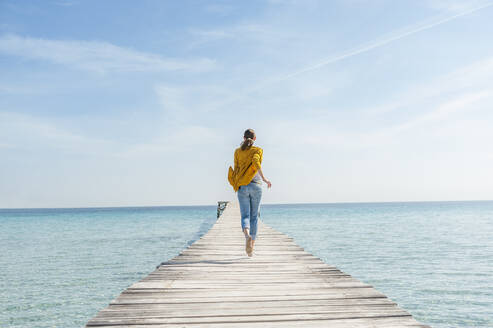 Rückenansicht einer Frau, die barfuß auf einem Steg läuft, Mallorca, Spanien - DIGF10335