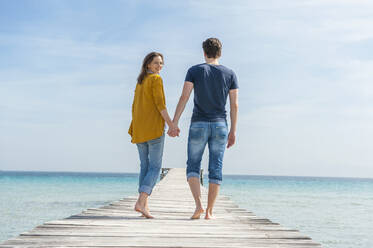 Couple walking hand in hand on jetty, Mallorca, Spain - DIGF10348