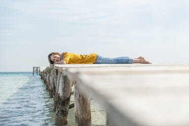 Happy woman lying on jetty relaxing, Mallorca, Spain - DIGF10351