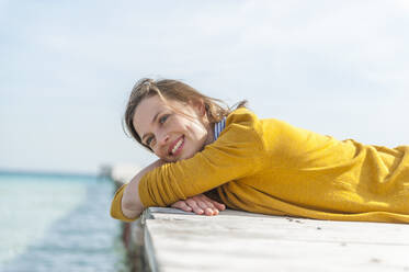 Portrait of happy woman lying on jetty relaxing, Mallorca, Spain - DIGF10352