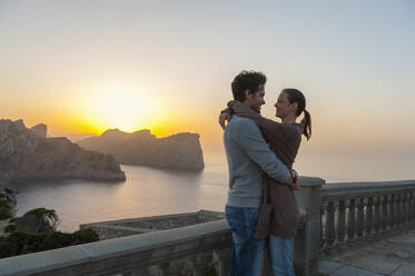 Couple standing on terrace by sunset hugging each other, Cap Formentor, Mallorca, Spain - DIGF10356