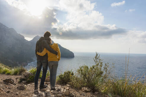 Back view of couple standing arm in arm looking to the sea, Mallorca, Spain - DIGF10358