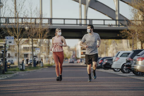 Junges Paar joggt während des Coronavirus auf der Straße in der Stadt - STDF00230