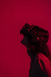 Frau mit Virtual-Reality-Headset vor rotem Hintergrund - EGAF00007