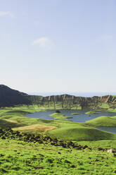 Idyllic view of lake amidst mountains against sky on sunny day, Corvo, Azores, Portugal - FVSF00234