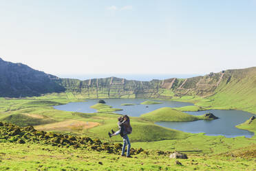 Full length of couple kissing while standing near lake and mountains against clear sky on sunny day, Corvo, Azores, Portugal - FVSF00236