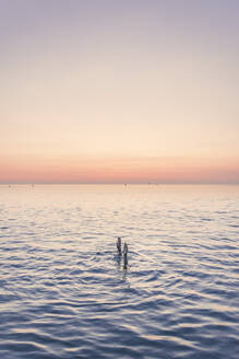 Hände eines jungen Mädchens im Mittelmeer gegen den Himmel bei Sonnenaufgang - FVSF00260