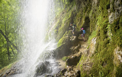 Junge und Mädchen wandern auf einer Felsformation unter dem Uracher Wasserfall im Wald - DIKF00496