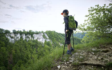 Junge steht mit Wanderstöcken am Rande der Hochebene und betrachtet die Landschaft der Schwäbischen Alb - DIKF00497