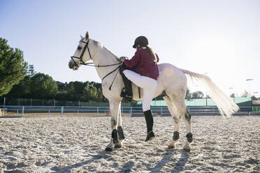 Mädchen in voller Länge auf einem weißen Pferd auf einer Ranch an einem sonnigen Tag - ABZF03106