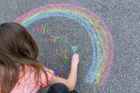 Girl painting rainbow on street with text 'Everything will fall into place' - SARF04557