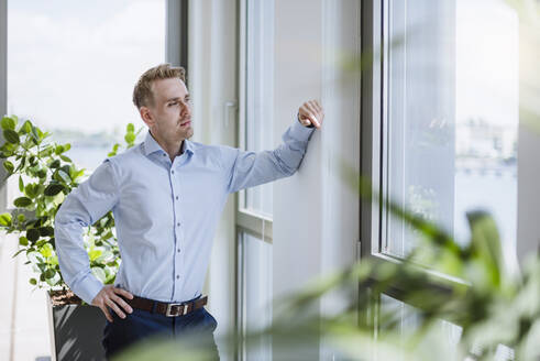 Geschäftsmann schaut im Büro aus dem Fenster - DIGF10375