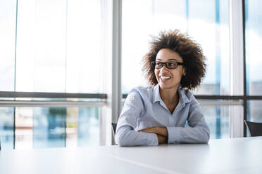 Smiling young businesswoman sitting at table in conference room - DIGF10389