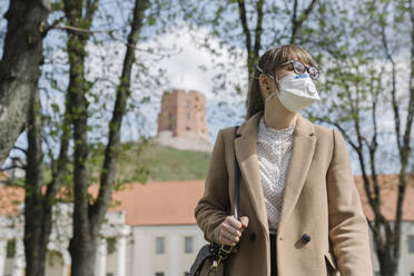 Frau mit FFP2-Maske schaut seitwärts in die Stadt - AHSF02512