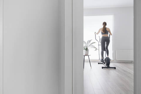 Frau beim Training auf dem Ellipsentrainer zu Hause, lizenzfreies Stockfoto