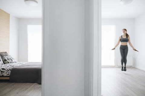 Woman during workout using jumping rope at home stock photo