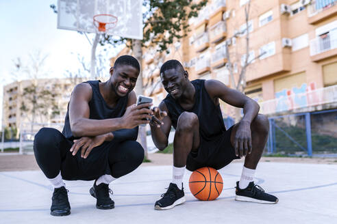 Basketballspieler benutzen Smartphone auf dem Basketballplatz - EGAF00015