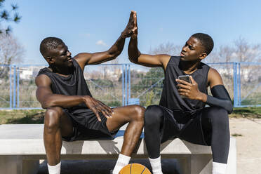 Basketballspieler, die sich auf einem Basketballplatz im Freien die Hände reichen - EGAF00023