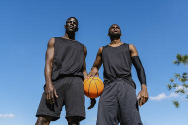 Young men holding basketball on basketball court - EGAF00024